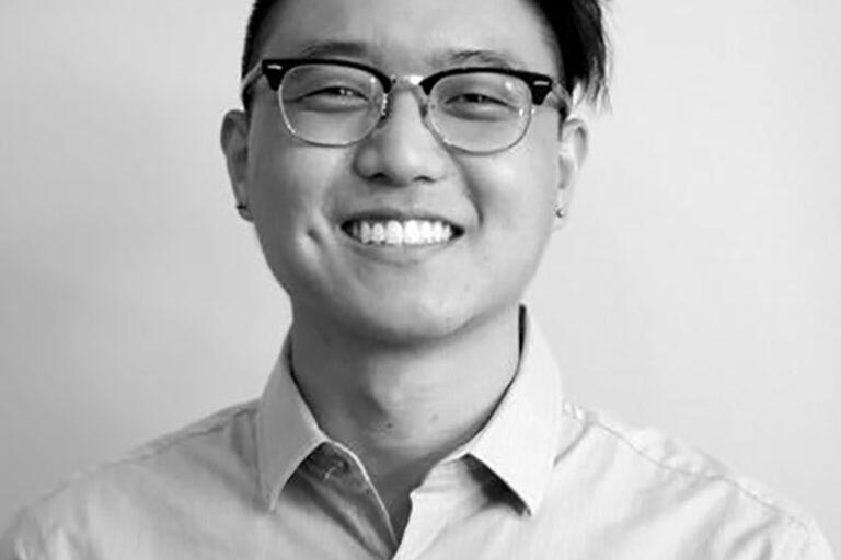 Black and white image of Andrew Kim wearing glasses and smiling.