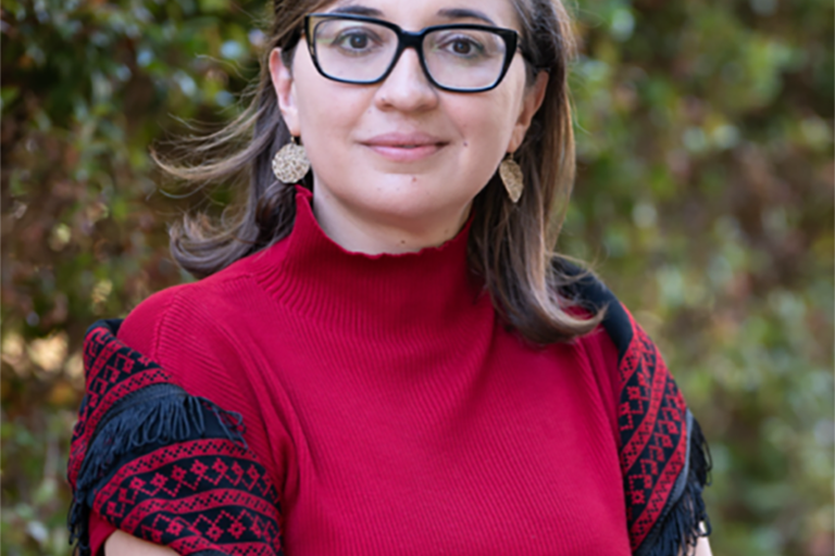 Areej Sabbagh-Khoury with black glasses smiling with arms crossed