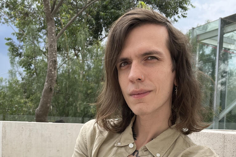 Chris with medium length hair, nose ring and beige shirt